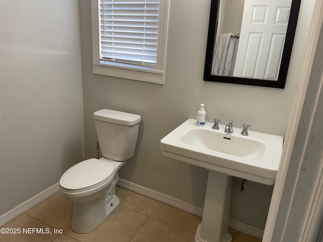 half bathroom featuring tile patterned floors, toilet, and baseboards