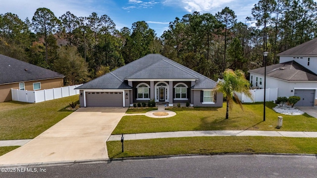 view of front of property with driveway, an attached garage, fence, and a front lawn