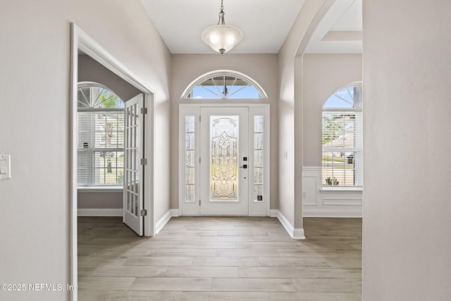 foyer entrance featuring a healthy amount of sunlight, light wood finished floors, and baseboards