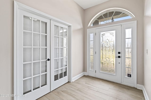 foyer with french doors, wood finished floors, and baseboards