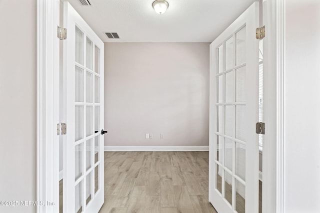 interior space featuring baseboards, visible vents, wood finished floors, and french doors