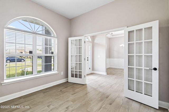 spare room with a wealth of natural light, french doors, baseboards, and wood finished floors