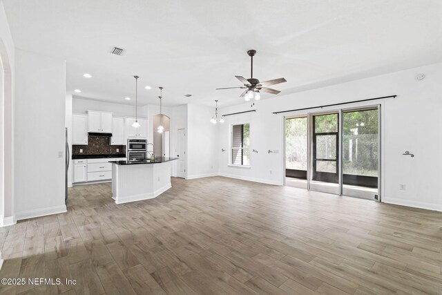 kitchen with dark countertops, light wood-style floors, open floor plan, and decorative backsplash