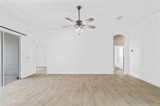 unfurnished room with light wood-style floors, arched walkways, visible vents, and a ceiling fan