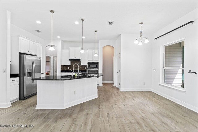 kitchen featuring appliances with stainless steel finishes, arched walkways, visible vents, and dark countertops