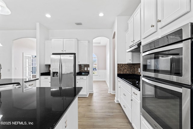 kitchen featuring dark countertops, arched walkways, and stainless steel appliances