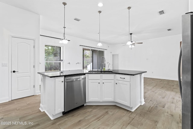 kitchen with dark countertops, visible vents, stainless steel appliances, and a sink