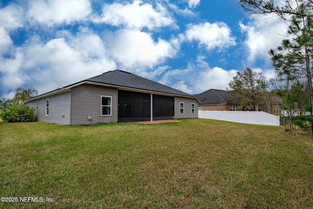 rear view of house with a sunroom, fence, and a lawn