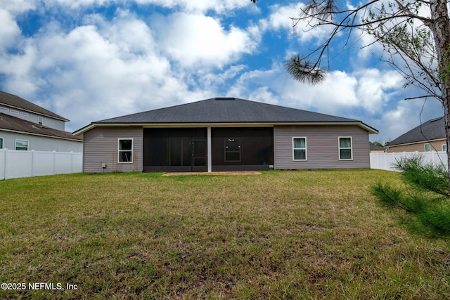 rear view of house with a sunroom, fence, and a lawn