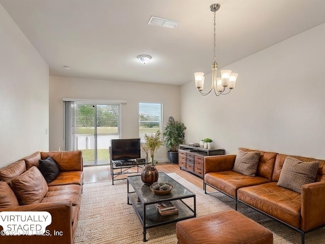 living area featuring light wood-style floors, visible vents, and a chandelier