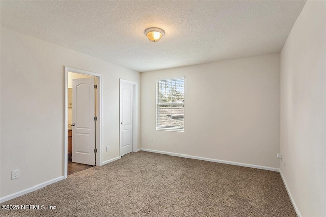 carpeted spare room with a textured ceiling and baseboards