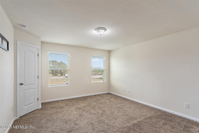 unfurnished room featuring a textured ceiling, carpet, and baseboards