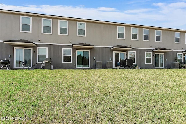 back of house with cooling unit, a yard, and stucco siding