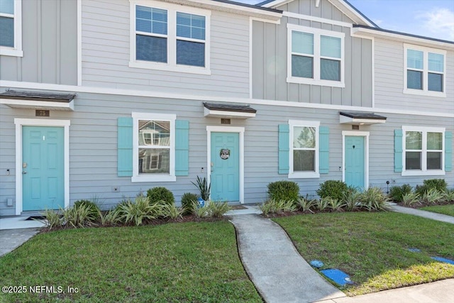 multi unit property featuring a front lawn and board and batten siding