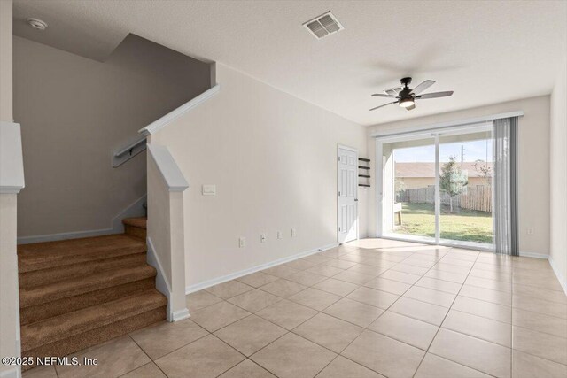 interior space with light tile patterned floors, visible vents, baseboards, a ceiling fan, and stairway