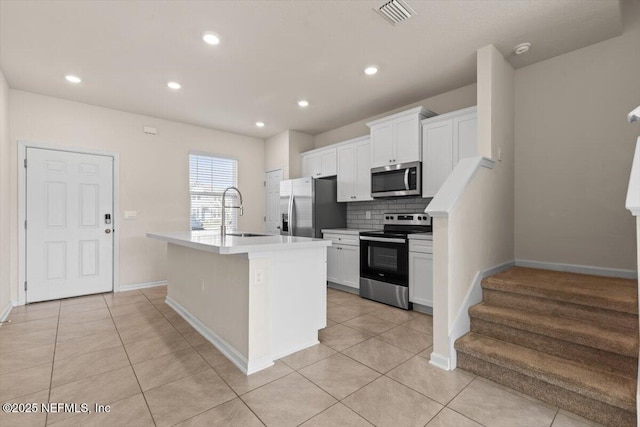 kitchen with a sink, visible vents, appliances with stainless steel finishes, tasteful backsplash, and an island with sink