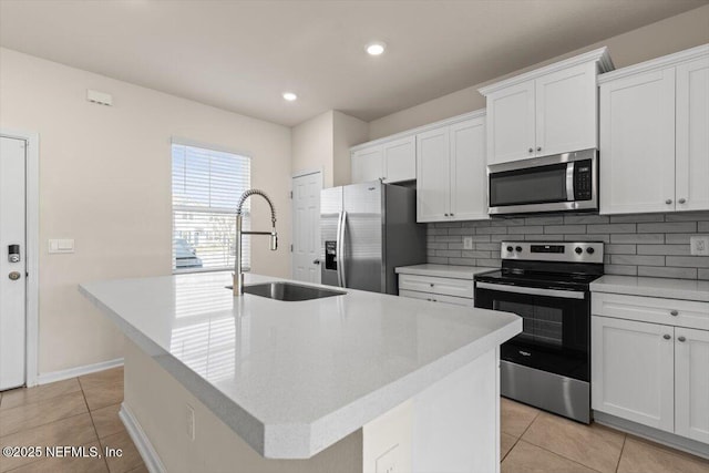 kitchen with light tile patterned floors, a kitchen island with sink, stainless steel appliances, a sink, and backsplash