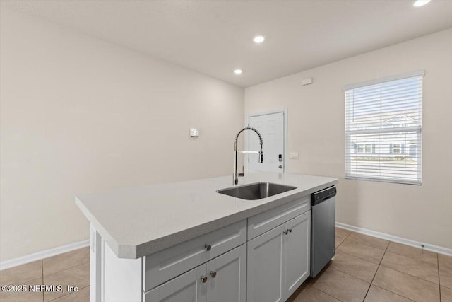 kitchen with a center island with sink, light tile patterned floors, a sink, dishwasher, and baseboards