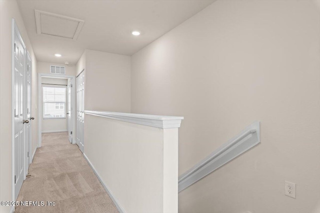 corridor featuring recessed lighting, light colored carpet, visible vents, baseboards, and attic access