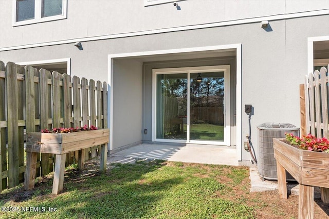 entrance to property with central air condition unit, fence, and stucco siding