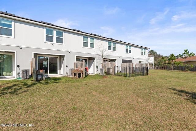 rear view of house featuring a lawn, cooling unit, fence, and stucco siding