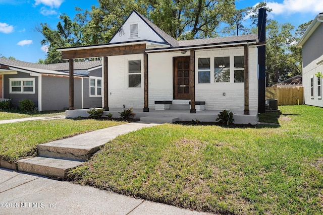 view of front facade with a porch, brick siding, fence, and a front lawn