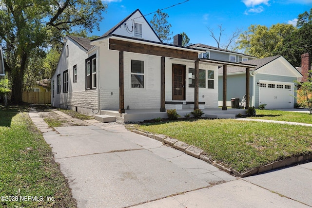 view of front facade featuring a garage, covered porch, driveway, a front lawn, and a chimney