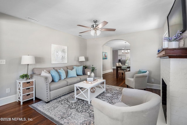 living area with baseboards, arched walkways, wood finished floors, and ceiling fan with notable chandelier