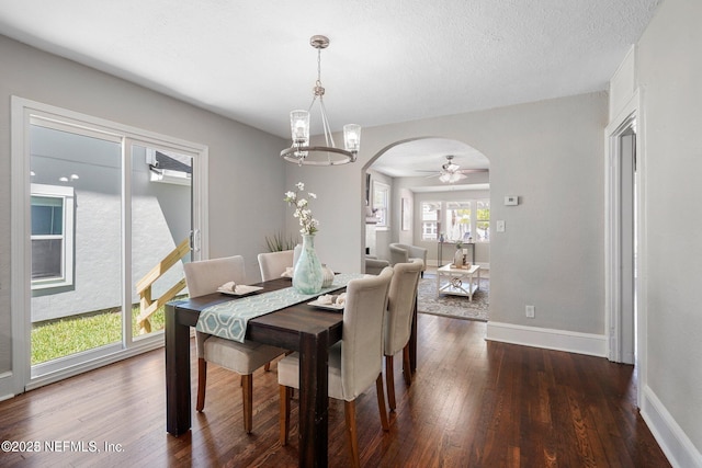 dining area featuring arched walkways, dark wood finished floors, a textured ceiling, and baseboards