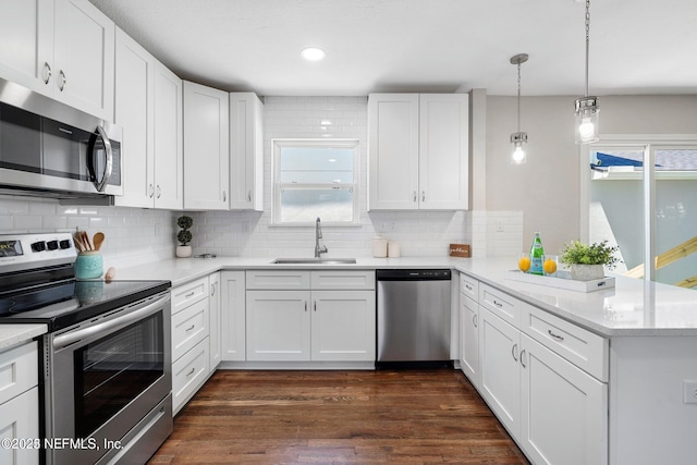 kitchen featuring a peninsula, dark wood-style flooring, a sink, white cabinetry, and appliances with stainless steel finishes