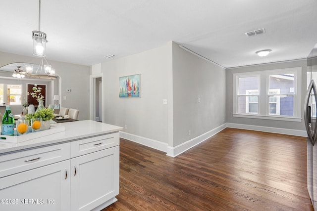 kitchen featuring dark wood-type flooring, visible vents, white cabinets, baseboards, and pendant lighting