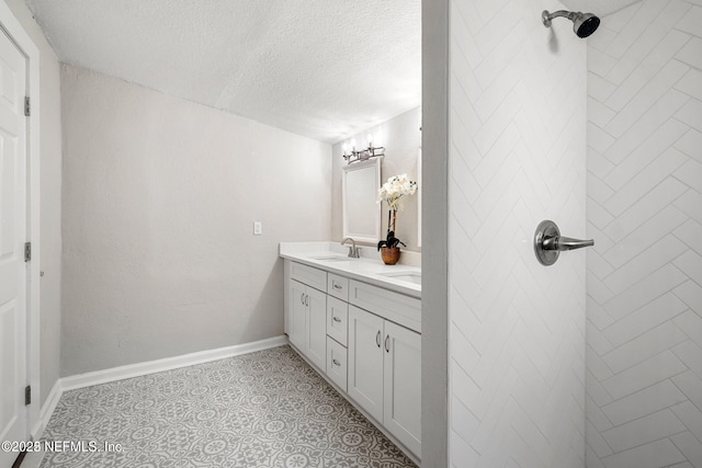 bathroom featuring double vanity, baseboards, tile patterned flooring, a textured ceiling, and a sink