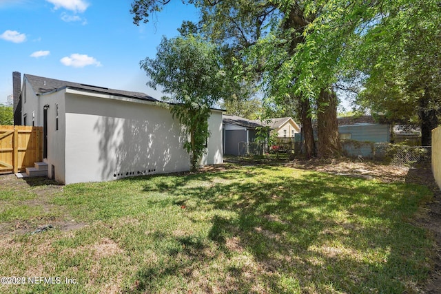 exterior space with fence, a lawn, and stucco siding