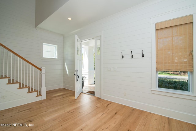 entrance foyer featuring recessed lighting, wood walls, light wood-type flooring, baseboards, and stairs