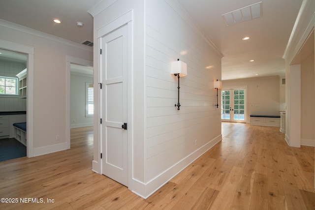 hall featuring light wood finished floors, visible vents, and crown molding