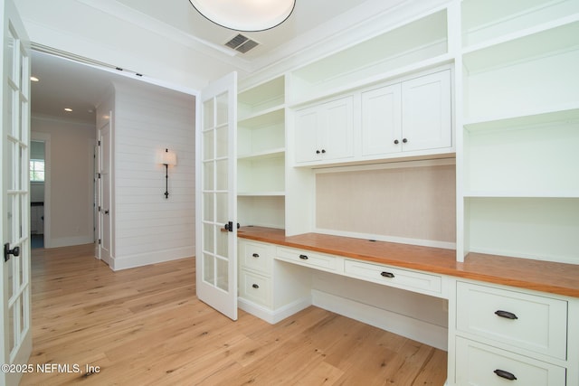 unfurnished office featuring visible vents, ornamental molding, french doors, built in study area, and light wood finished floors