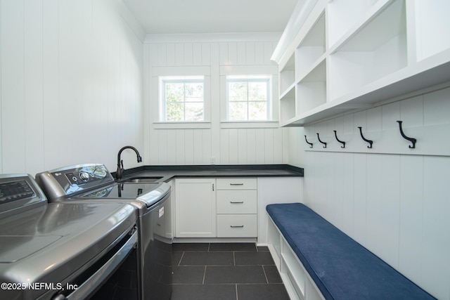 clothes washing area featuring cabinet space, a sink, dark tile patterned floors, and separate washer and dryer