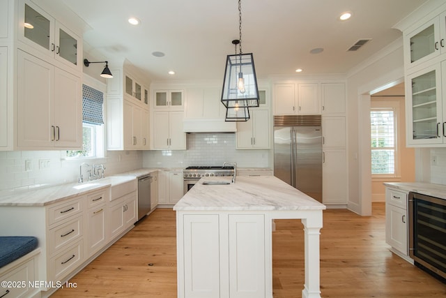 kitchen with beverage cooler, visible vents, high end appliances, light wood-type flooring, and a sink