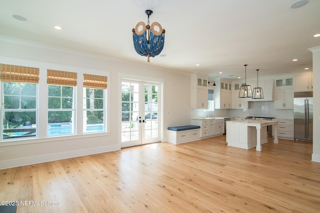 kitchen with built in fridge, light wood-style flooring, ornamental molding, french doors, and tasteful backsplash