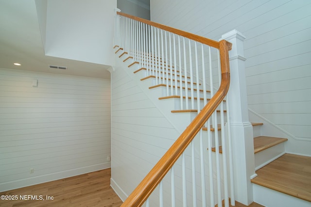 stairway featuring recessed lighting, wood walls, wood finished floors, visible vents, and baseboards