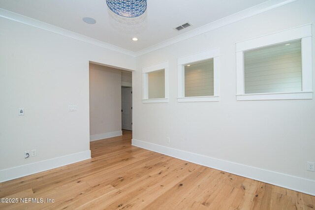 empty room featuring ornamental molding, visible vents, baseboards, and wood finished floors