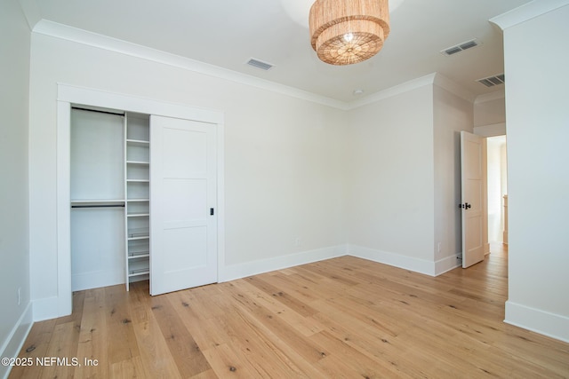 unfurnished bedroom with light wood finished floors, baseboards, visible vents, and ornamental molding