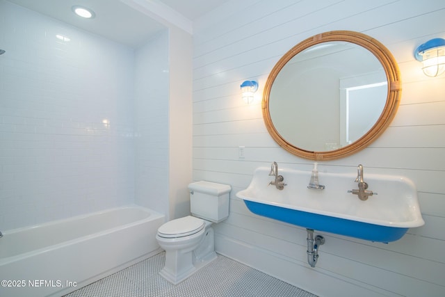 bathroom with wooden walls, toilet, tile patterned floors, a sink, and recessed lighting