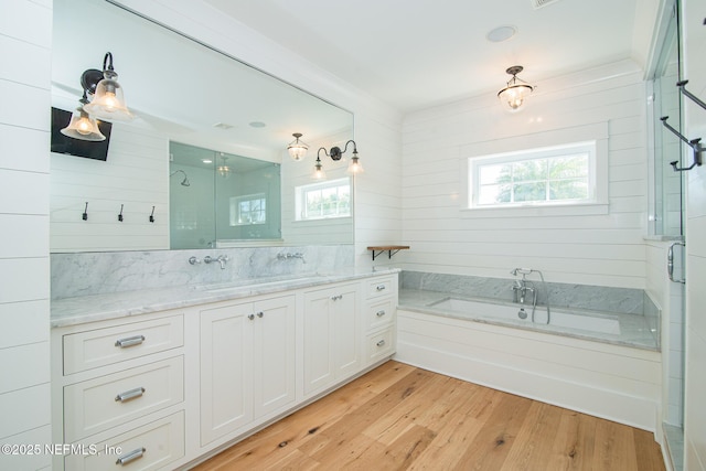 bathroom with a wealth of natural light, a stall shower, vanity, and wood finished floors