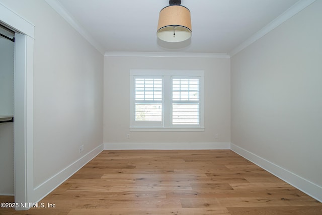 empty room with crown molding, light wood-style flooring, and baseboards