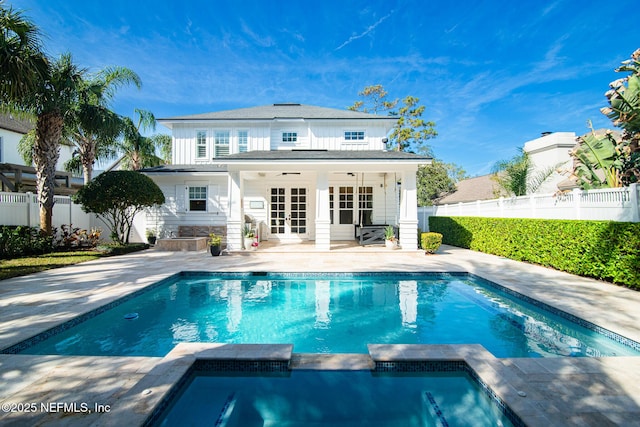 rear view of house with a patio, a fenced backyard, a pool with connected hot tub, a ceiling fan, and french doors