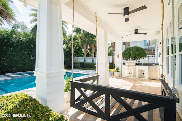 view of patio / terrace with ceiling fan, area for grilling, fence, a pool with connected hot tub, and exterior kitchen