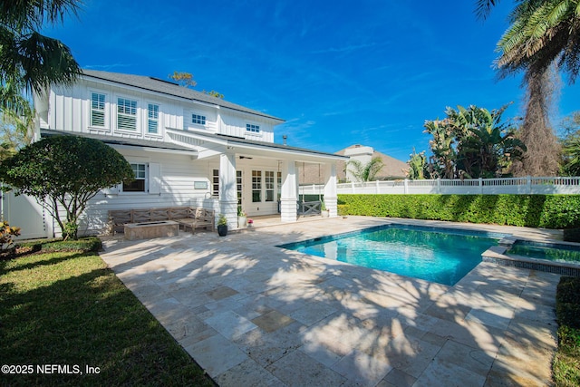 view of swimming pool featuring a fenced backyard, a pool with connected hot tub, and a patio