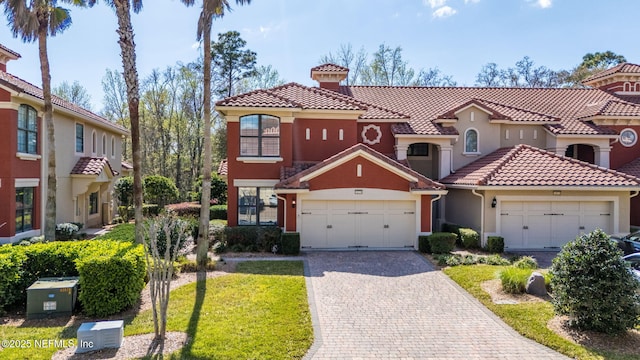 mediterranean / spanish home featuring stucco siding, a tiled roof, and decorative driveway