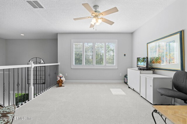 home office with visible vents, light carpet, a textured ceiling, and baseboards